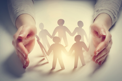 Paper people surrounded by hands in gesture of protection. Concept of insurance