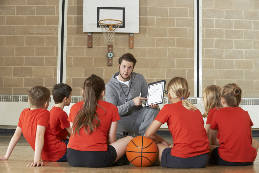 Coach Giving Team Talk To Elementary School Basketball Team