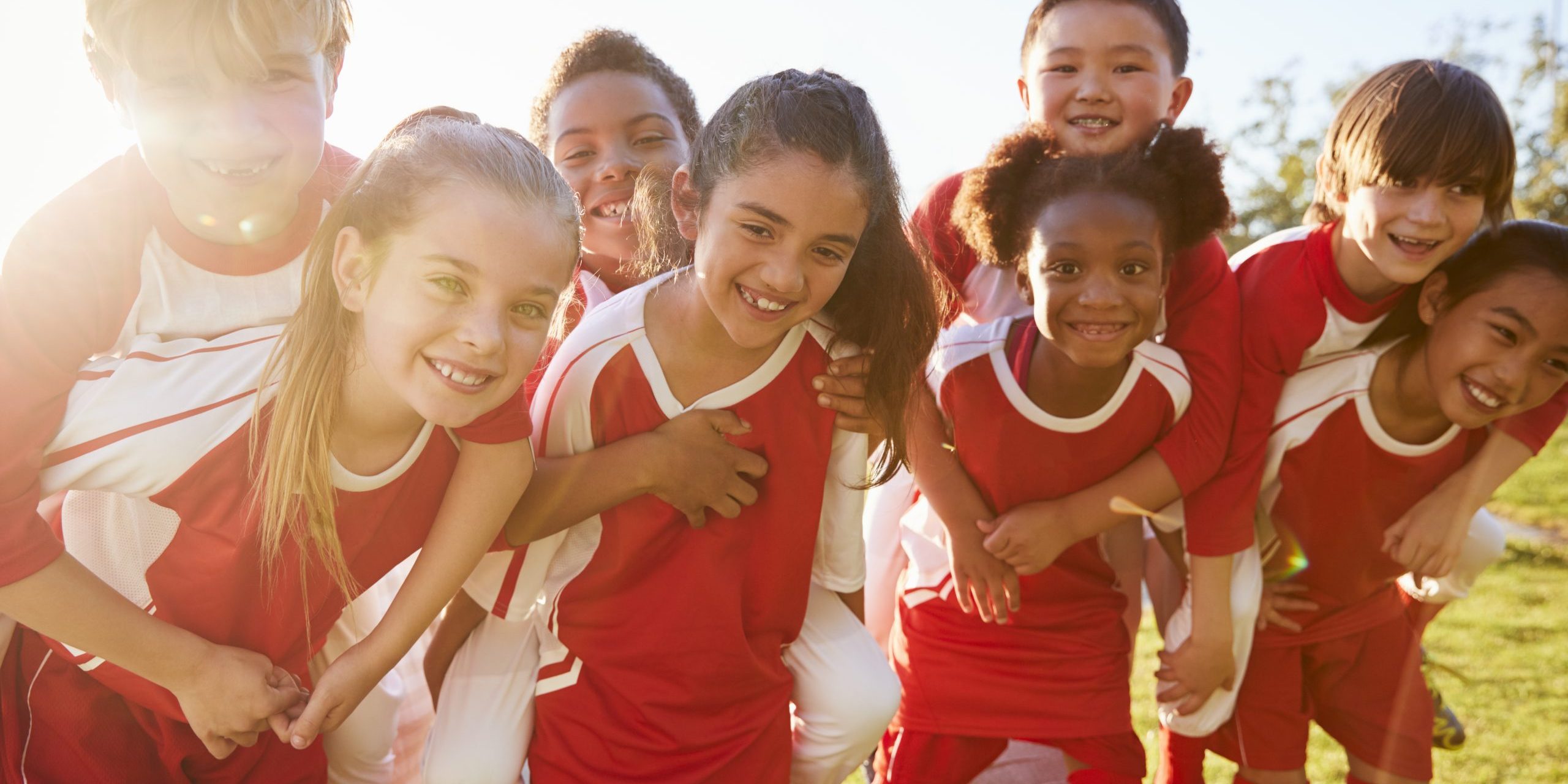 Kids in elementary school sports team piggybacking outdoors